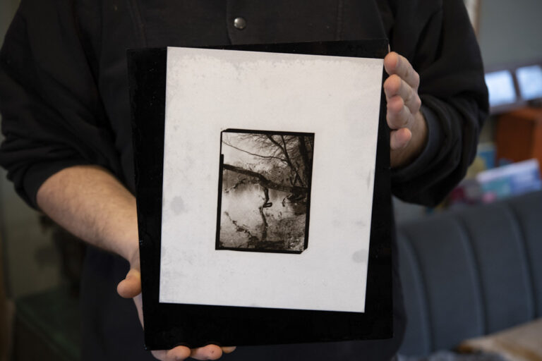 two hands holding a analog carbin print depicting a nature scene