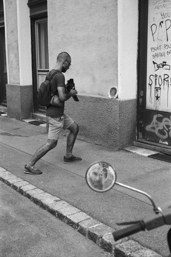 street photography scene with a person taking a picture of an object at a wall