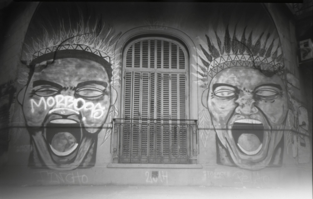 black and white pinhole style picture showing a mural depicting two faces.